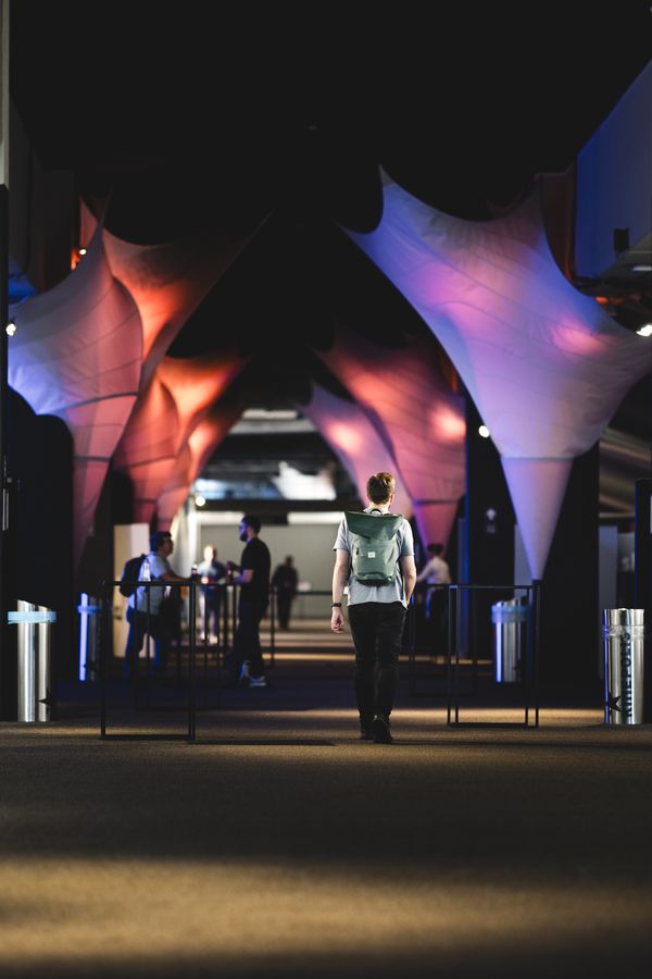 The Kinepolis entrance at night, its canopy lit pink and blue, with visitors walking in under a dark sky.